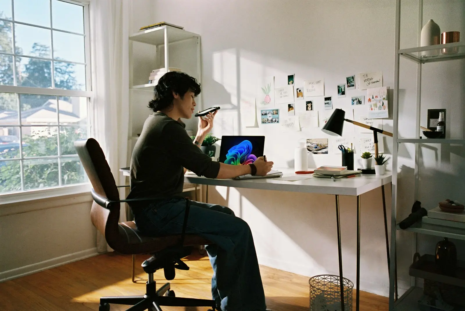 A person at a sunlit desk talking on the phone