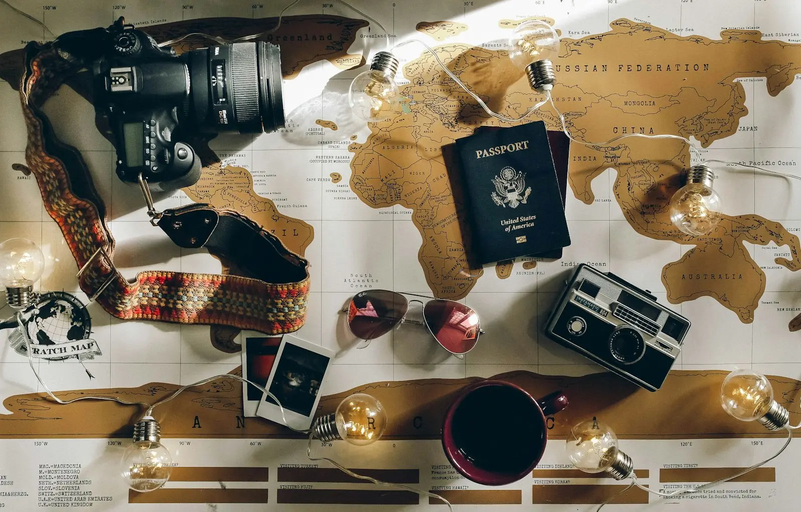 A passport resting on a world map beside a camera