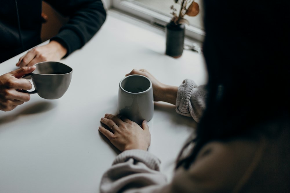 Two people talking over coffee at a table