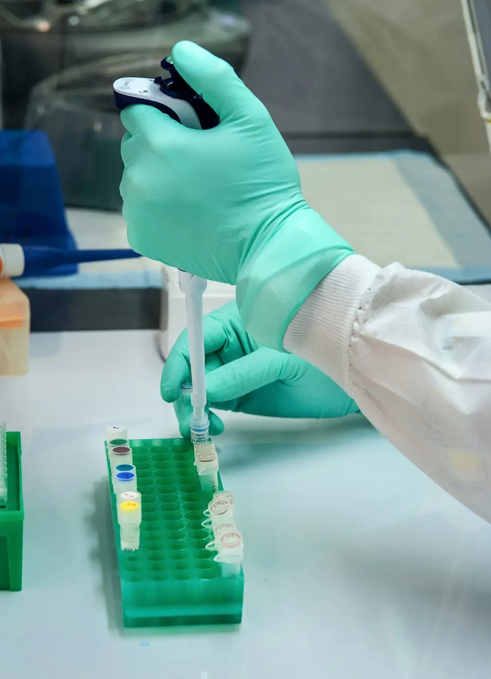 Gloved hands pipetting into sample vials